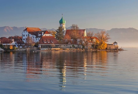 Peninsula with the parish church of St. George in front of the Alps in the evening sun