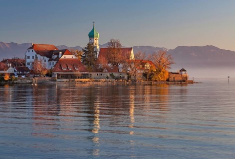 Peninsula with the parish church of St. George in front of the Alps in the evening sun