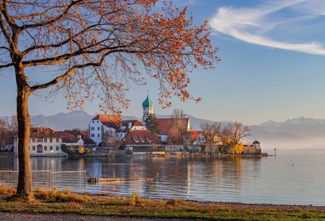 Peninsula with the parish church of St. George in front of the Alps in the evening sun