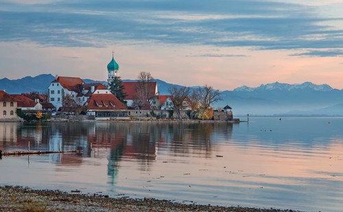 Peninsula with the parish church of St. George in front of the Alps in the evening sun