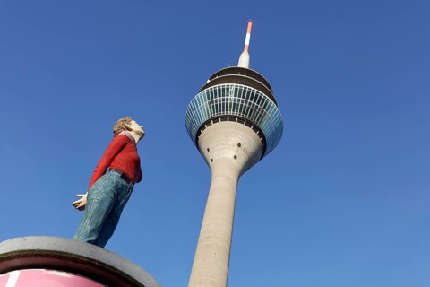 Realistic female figure on an advertising pillar in front of the Rhine Tower