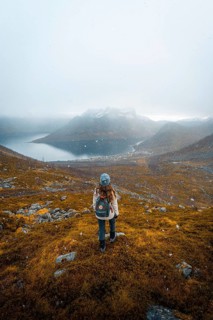 Woman looking at the village Fjordbotn and a prominent and pointed mountain