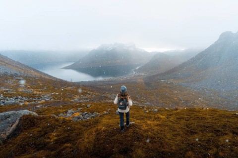 Woman looking at the village Fjordbotn and a prominent and pointed mountain