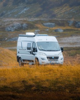 Campervan parked on grassed parking lot near Kafjord