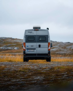 Campervan with rear view standing on parking lot near Kafjord