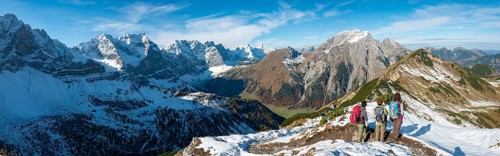 Three hikers on hiking trail with snow in autumn