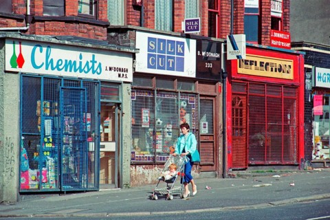 Woman with pram in front of barred shops