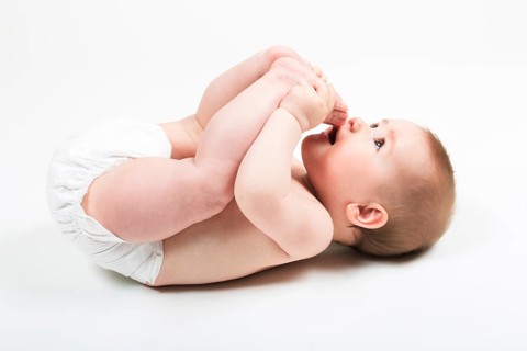 Baby lies on back and plays with his feet