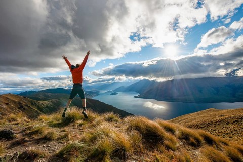 Hiker stretches his arms in the air and takes a leap in the air
