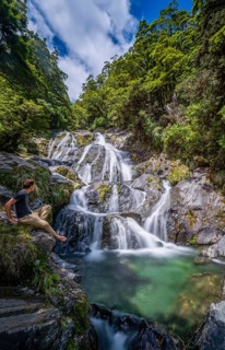 Young man sitting at a waterfall
