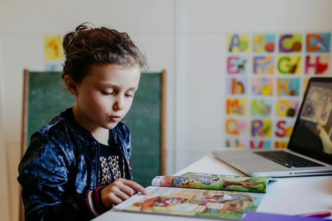 Little girl learning with reading book and laptop