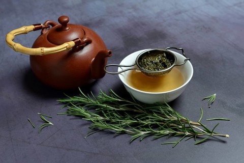 A cup of rosemary tea with tea strainer