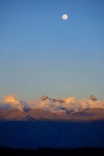 Mountain peak of the Andes above a cloud bank with full moon