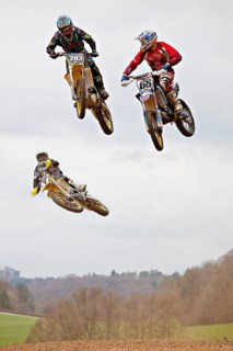 Three motocross machines in the air at the race