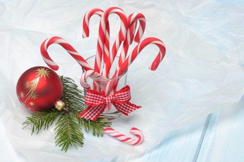Candy canes in glass and Christmas tree ball with fir branch