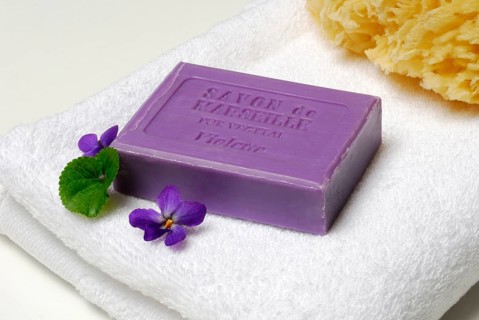 Violet soap and violet flowers on towel
