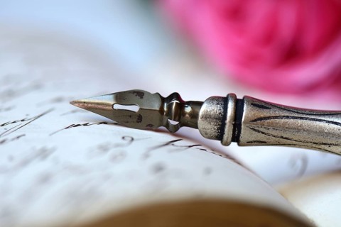 Pen and pencil with nib on book with old handwriting