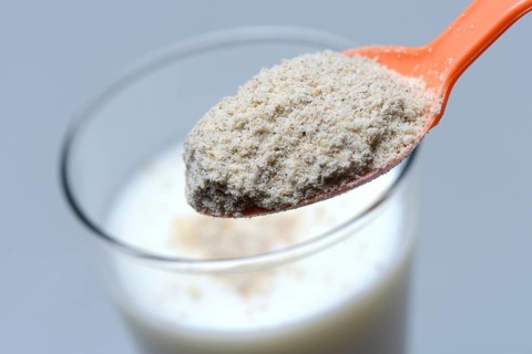 Tigernut flour in spoon and glass of milk