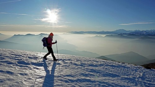 Hiker descending over snowfield from Monte Lema