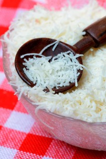 Grated Parmesan cheese in glass bowl with wooden spoon