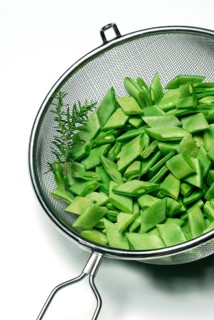 Sliced broad beans with savory in kitchen sieve
