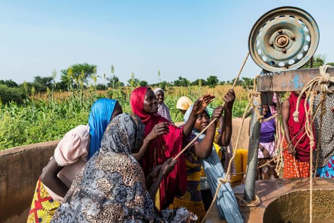 Colourful dressed women fetch water at the well