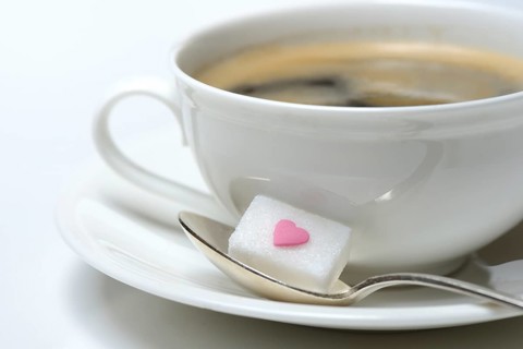 Sugar cube with sugar heart and cup of coffee