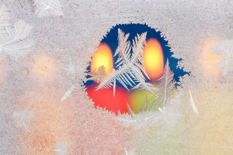 Ice flowers on glass pane in candlelight