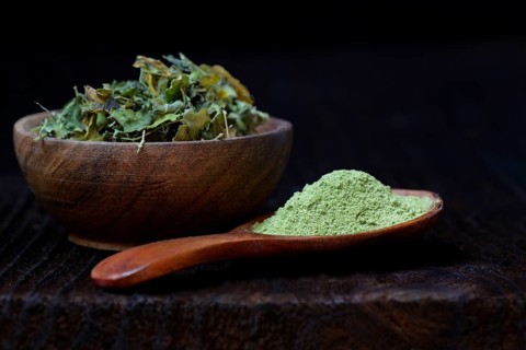 Moringa leaves in bowl and moringa powder in spoon