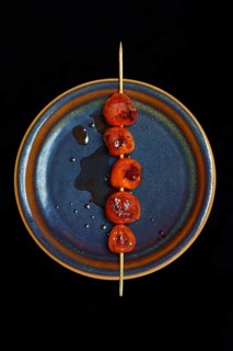 Roasted cherry tomatoes on skewer on plate