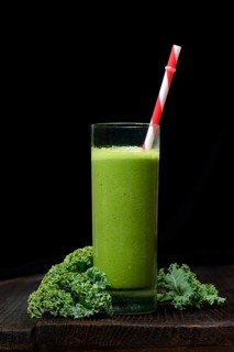 Kale smoothie in glass with drinking straw