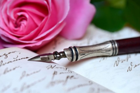 Pen and pencil with nib on book with old handwriting