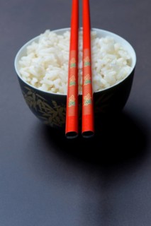 Boiled rice in bowl with chopsticks