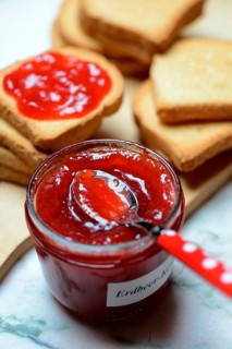 Strawberry jam in glass with spoon and rusk