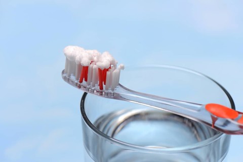 Sodium powder on toothbrush and glass with water