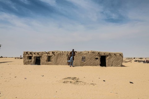 Man in front of traditional mud house