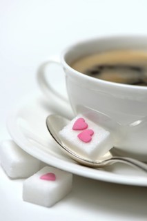 Sugar cube with sugar heart and cup of coffee