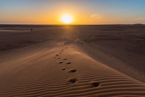 Footsteps in a sand dune at sunset