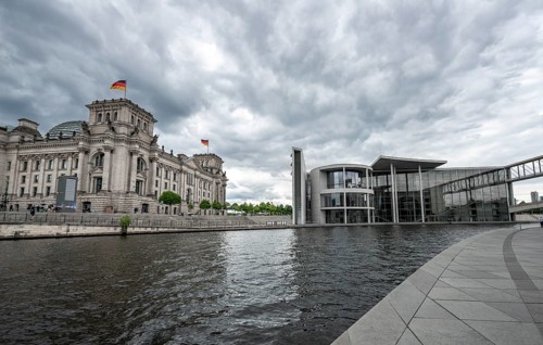 Reichstag building with waving German flag and Paul Loebe House on the Spree