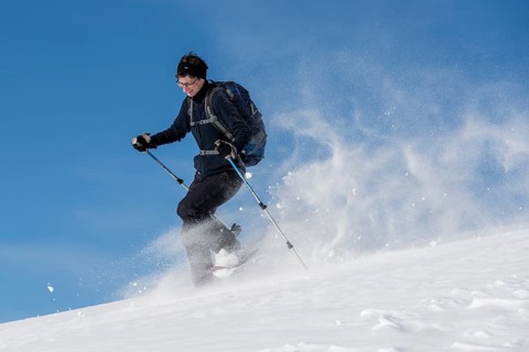 Woman with snowshoes walking through snow