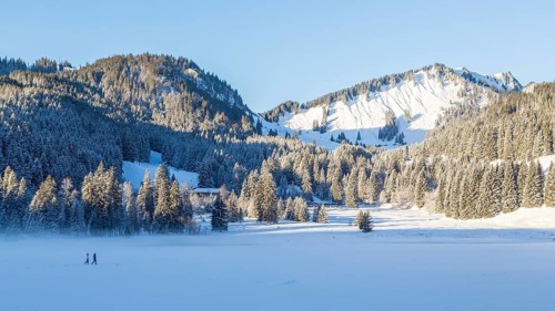 Frozen Spitzingsee in winter with walkers