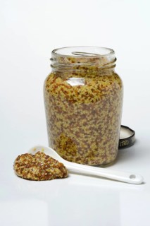 Coarse-grained mustard in glass with spoon