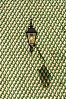 Shadow of a lantern on a green wooden lattice wall