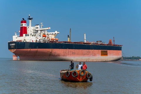 Little boat under a Huge container ship ready to break up