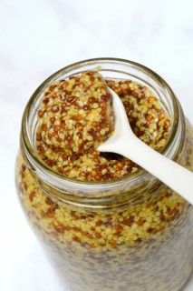 Coarse-grained mustard in glass with spoon