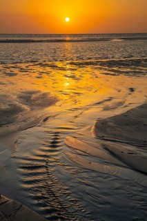 Sunset over tidal creek on sandy beach