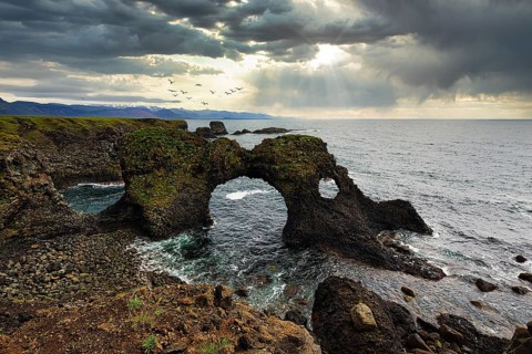 Eroded cliff at the Atlantic Ocean with Gatklettur and dramatic cloud formation