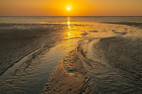 Sunset over tidal creek on sandy beach