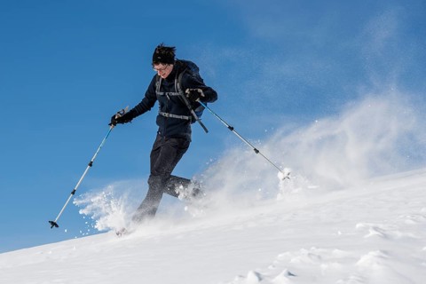Woman with snowshoes walking through snow