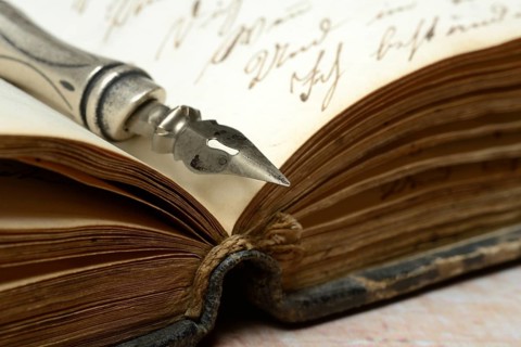 Penholder with quill on old diary